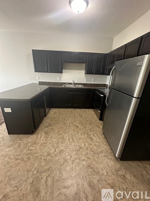 A kitchen with black cabinets and a silver refrigerator.