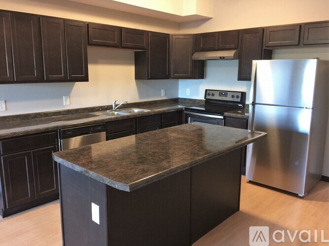 A kitchen with dark brown cabinets and a granite countertop.