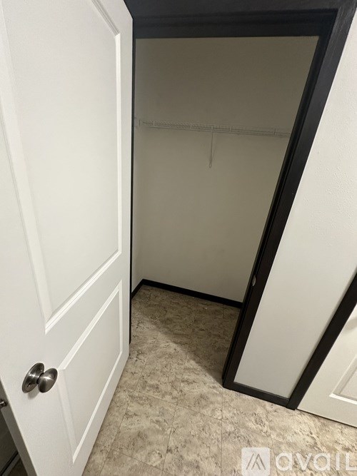 A white door with a silver handle is open to a dark room.