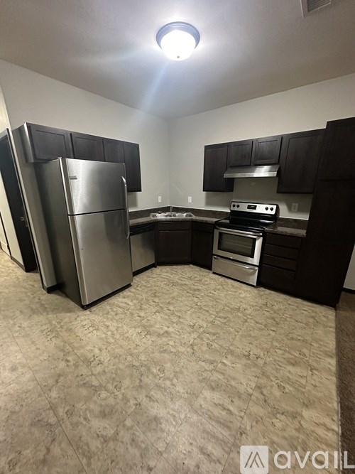 A kitchen with a refrigerator, oven, and stove.