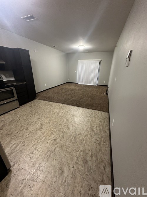 A room with a carpeted floor and a window with blinds.