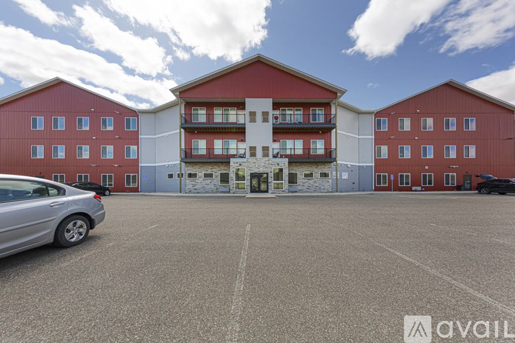 A parking lot with a silver car and a building with a red and white facade.