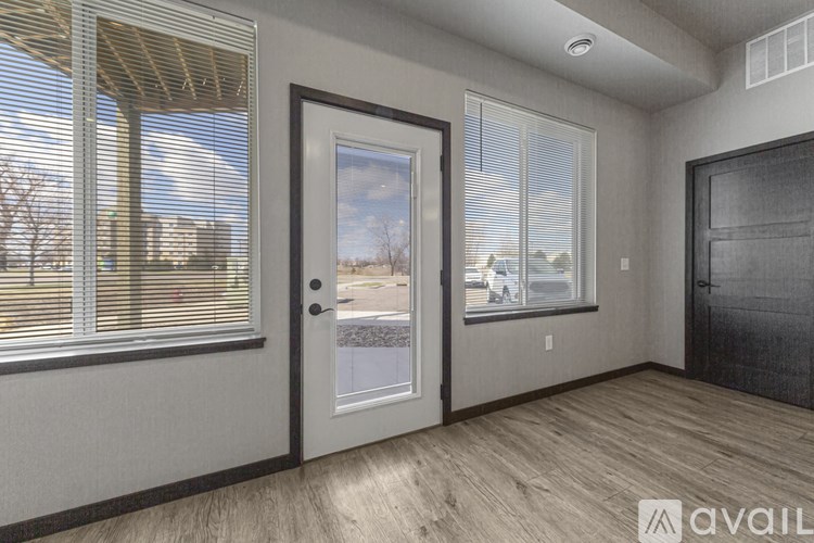 A room with a door, a window with blinds, and a wall with a picture frame.