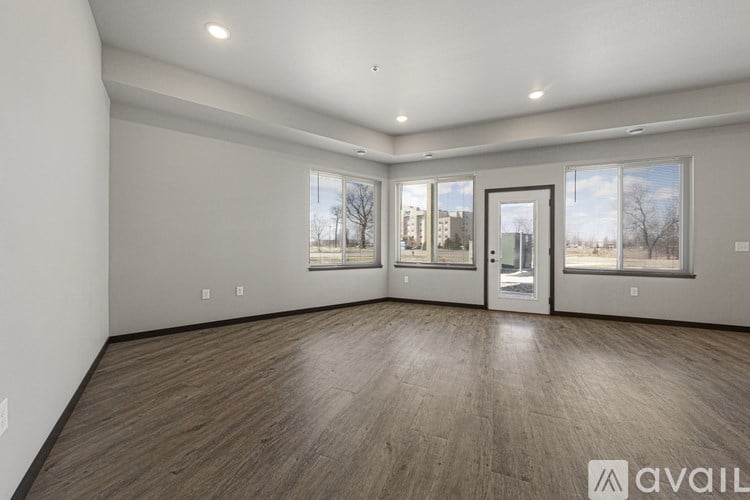A spacious room with wooden flooring and large windows.
