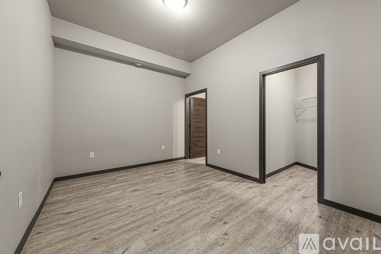 A spacious room with wood flooring and a large mirror on the wall.