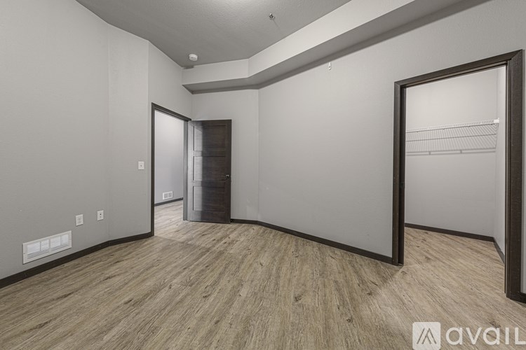A room with a wooden floor and a white wall with a door in the middle.