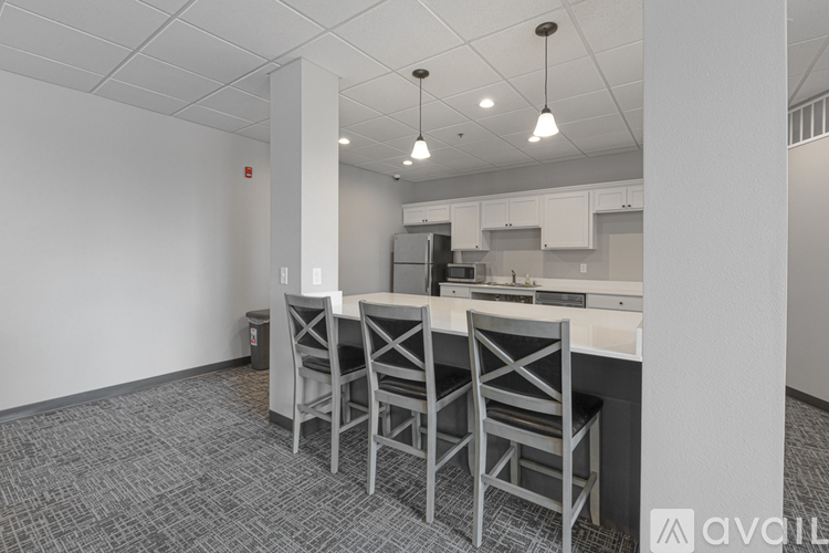 A kitchen area with a bar and chairs.