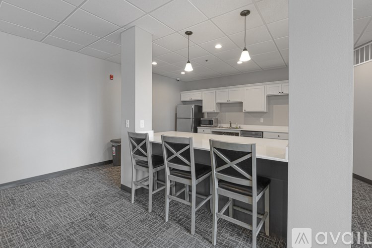 A kitchen area with a bar and chairs.