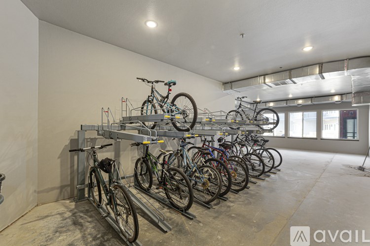 A room with a white wall and a bike rack with many bikes.