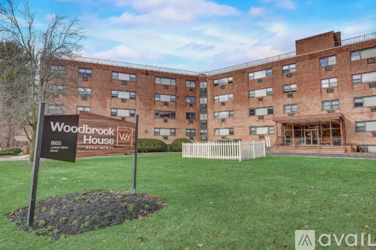 A sign for Woodbrook House stands in front of a brick building.