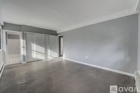 A spacious room with a grey floor and white walls, featuring a row of glass doors.