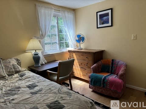 A bedroom with a bed, chair, and window.