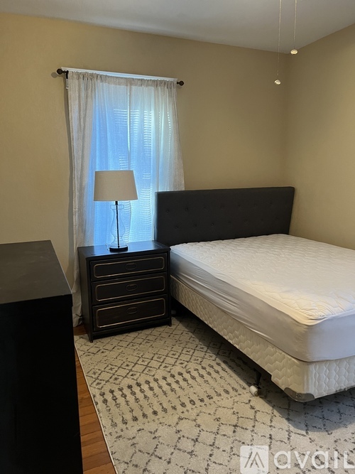A bedroom with a bed, nightstand, and lamp.