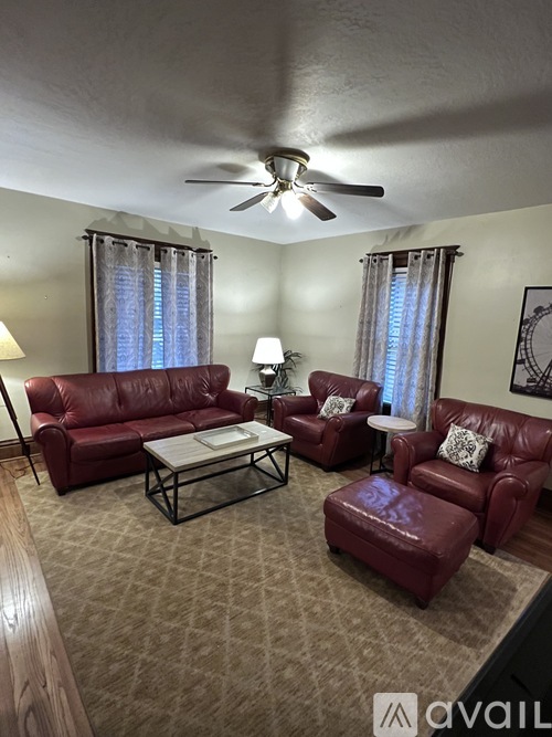 A living room with red leather furniture and a ceiling fan.