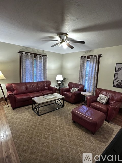 A living room with red leather furniture and a ceiling fan.