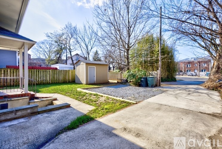 A residential area with a small building and a gravel path.
