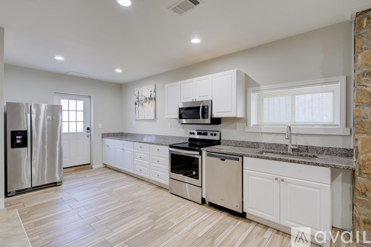 A kitchen with white cabinets and a stone wall.