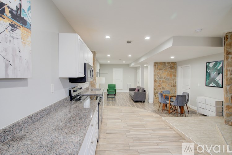 A modern kitchen with granite countertops and a dining area with chairs.