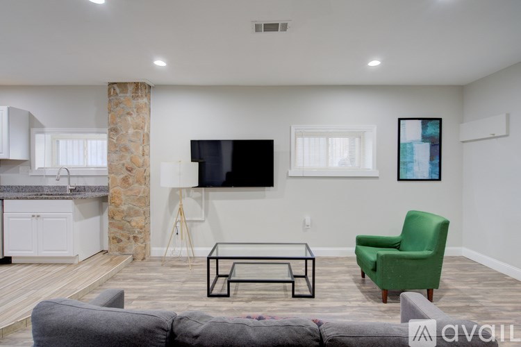 A living room with a grey couch, a green chair, and a black TV.