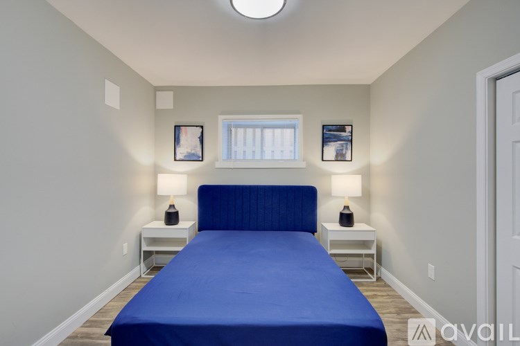 A bedroom with a blue bed and two white nightstands.