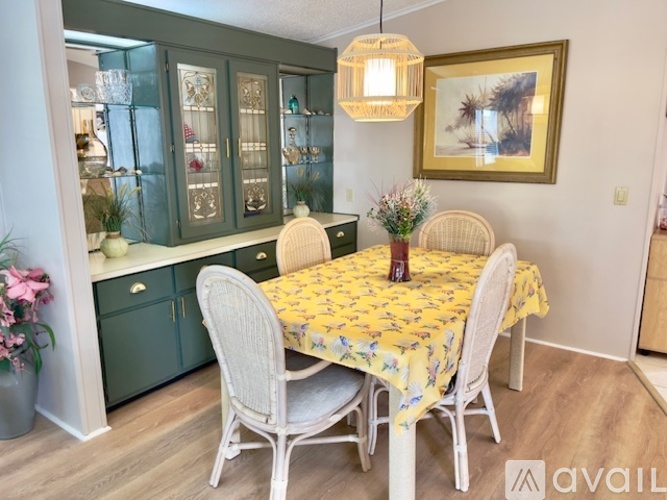 A dining room with a table set for two and a china cabinet.
