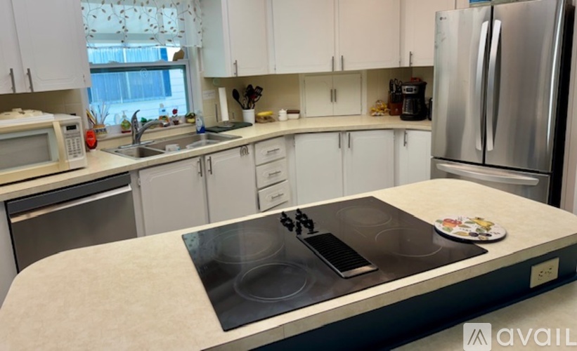 A kitchen with white cabinets and a stainless steel refrigerator.