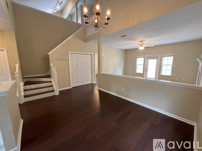 A spacious room with wooden floors and a staircase leading to the upper level.
