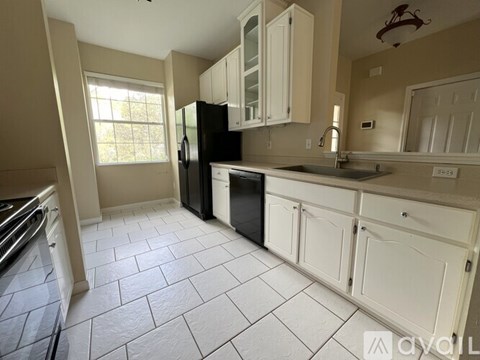 A kitchen with white cabinets and a black refrigerator.