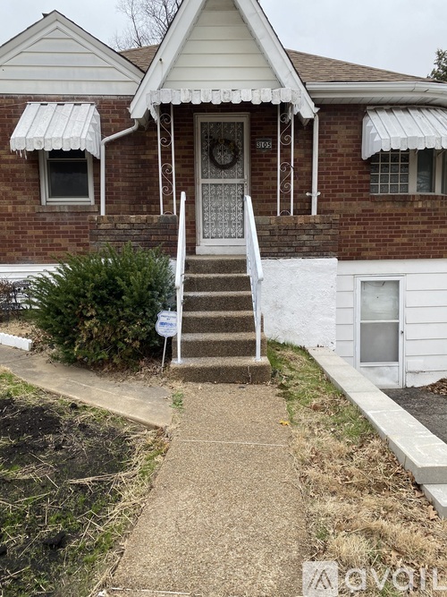 A white house with a brown roof and a white porch.