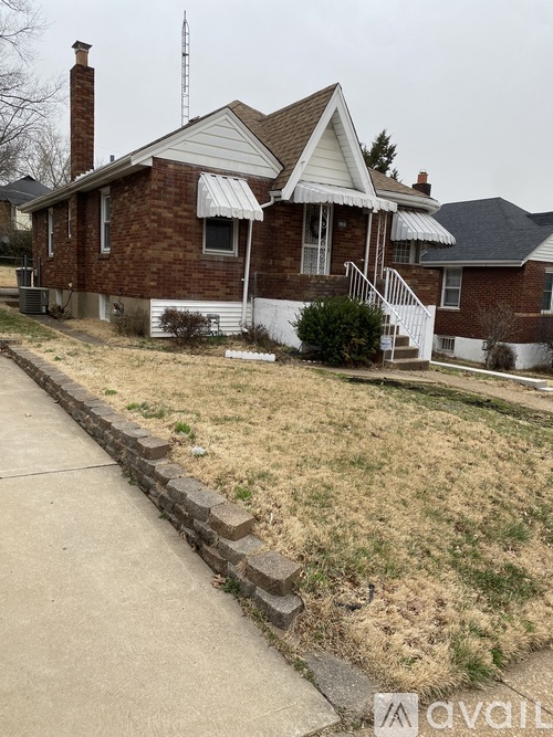 A brick house with a white roof and a white fence.