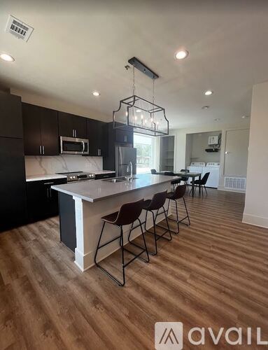 A kitchen with dark brown cabinets and a white island with a hanging light fixture.