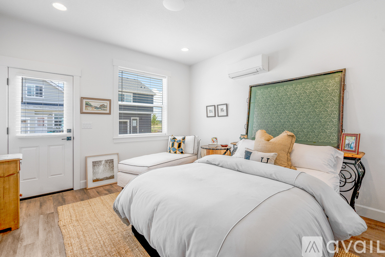 A bedroom with a large bed and a window with blinds.