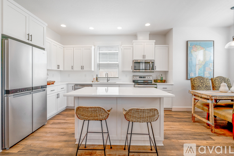 A kitchen with white cabinets and a white island with two stools.