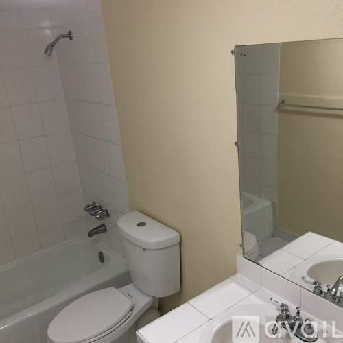 A white toilet sits next to a white bathtub in a bathroom.
