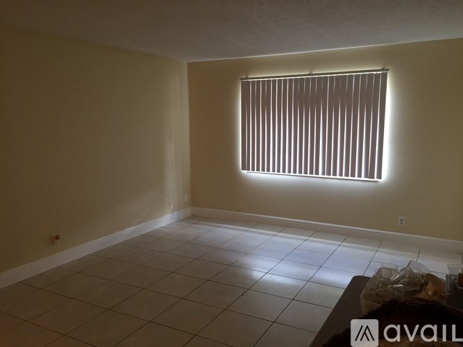 A room with a window covered by blinds and a tiled floor.