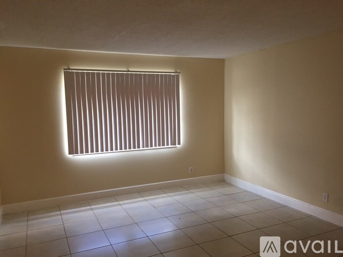 A room with a window covered by vertical blinds.
