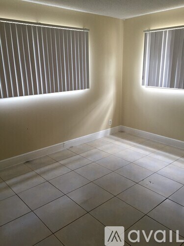 A room with tiled flooring and two windows with blinds.
