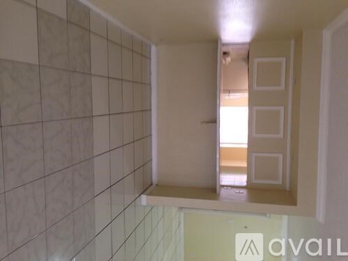 A bathroom with a tiled wall and a window.