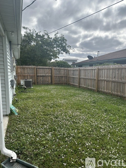 A backyard with a wooden fence and a grassy area with white flowers.