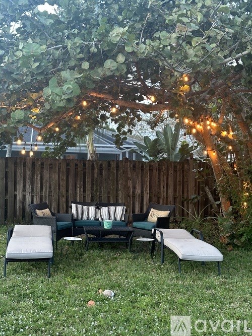 A backyard with a bench and a tree with lights.