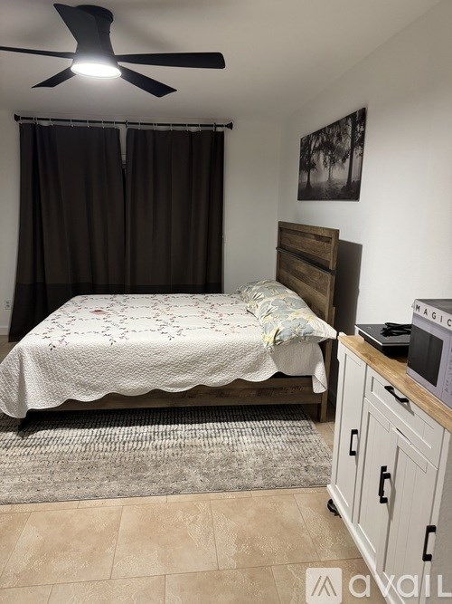 A bedroom with a bed, a ceiling fan, and a picture on the wall.