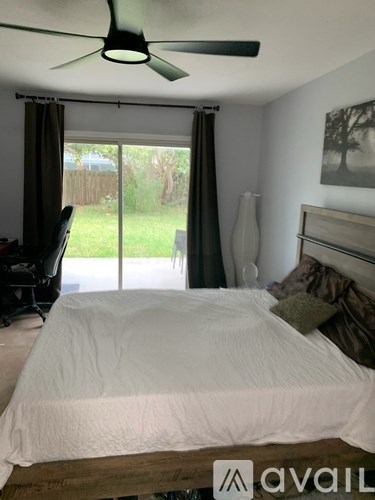 A bedroom with a bed, a ceiling fan, and a picture on the wall.