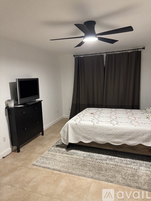 A bedroom with a bed, dresser, and sliding glass doors.