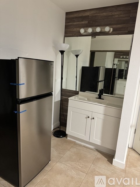 A black fridge stands next to a white cabinet in a kitchen.