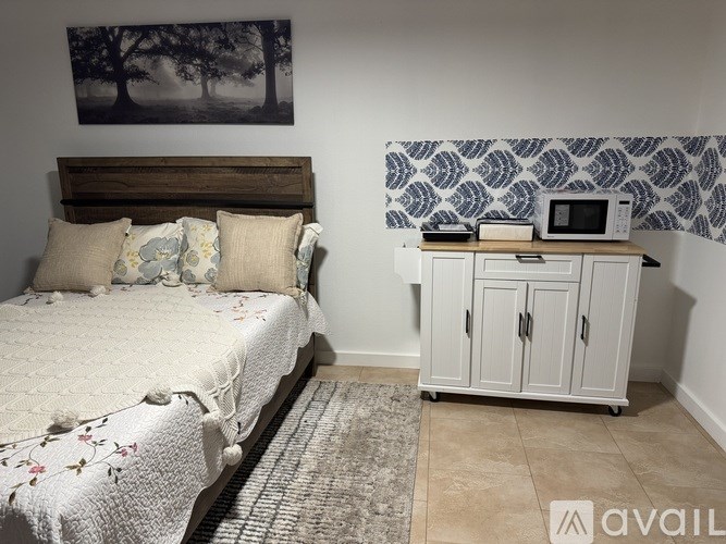 A bedroom with a bed, nightstand, and a painting on the wall.