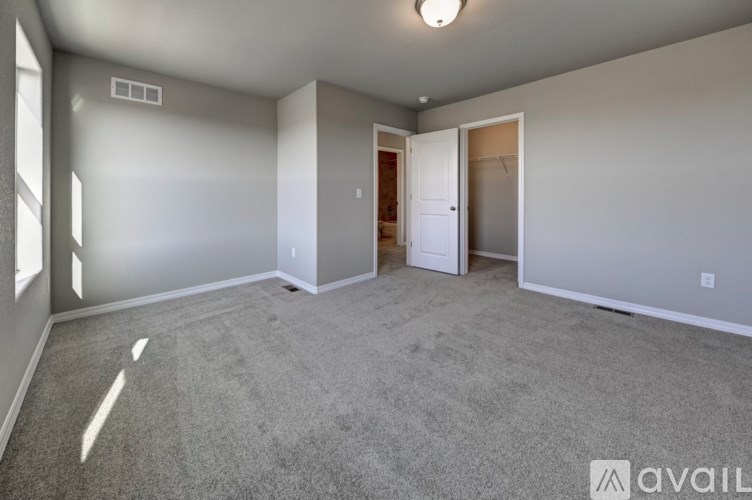 A spacious room with a carpeted floor and a single window on the left side.