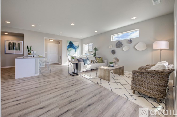 A spacious living room with a white sofa, a wooden floor, and a large window.