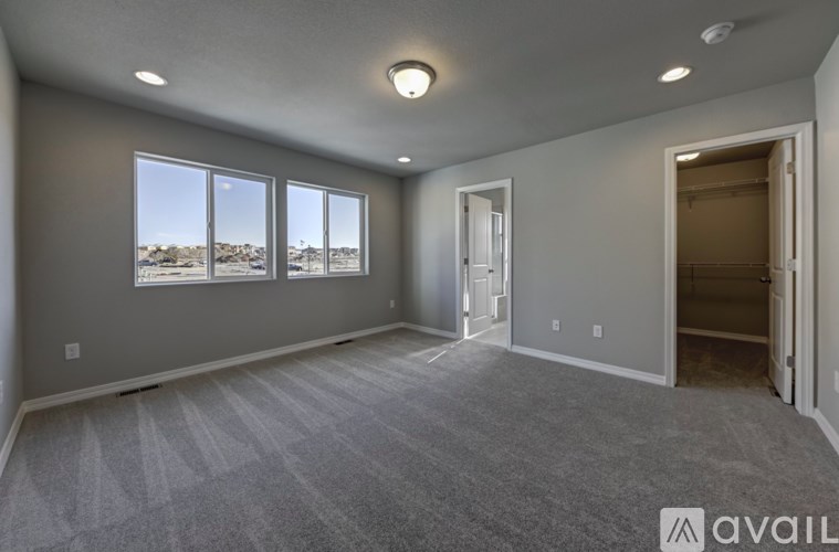 A spacious room with grey carpeting and a large window overlooking a desert landscape.