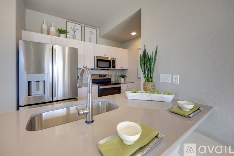 A modern kitchen with a stainless steel refrigerator and a sink with a green placemat on the counter.