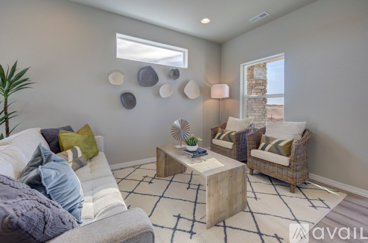 A living room with a grey couch, a wooden coffee table, and a fan.